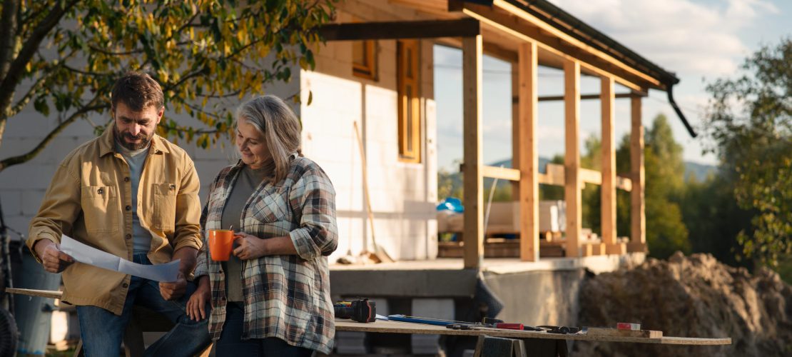 A mature couple having coffee break when working together on construction site of their new house.